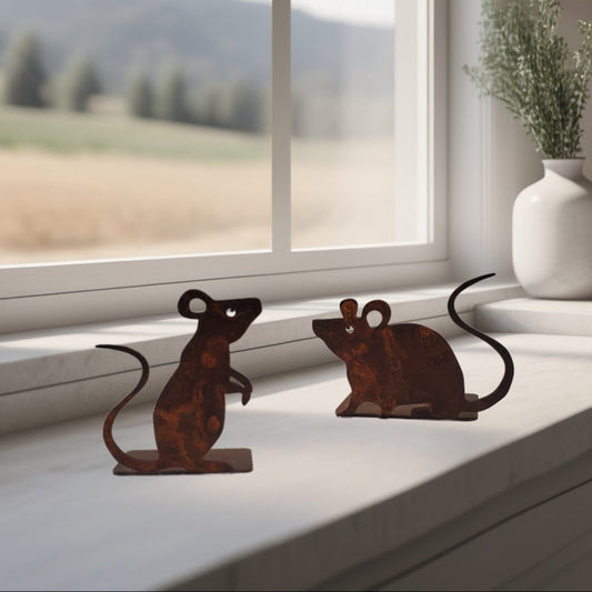 Two metal mouse sculptures on a windowsill with a scenic view outside.