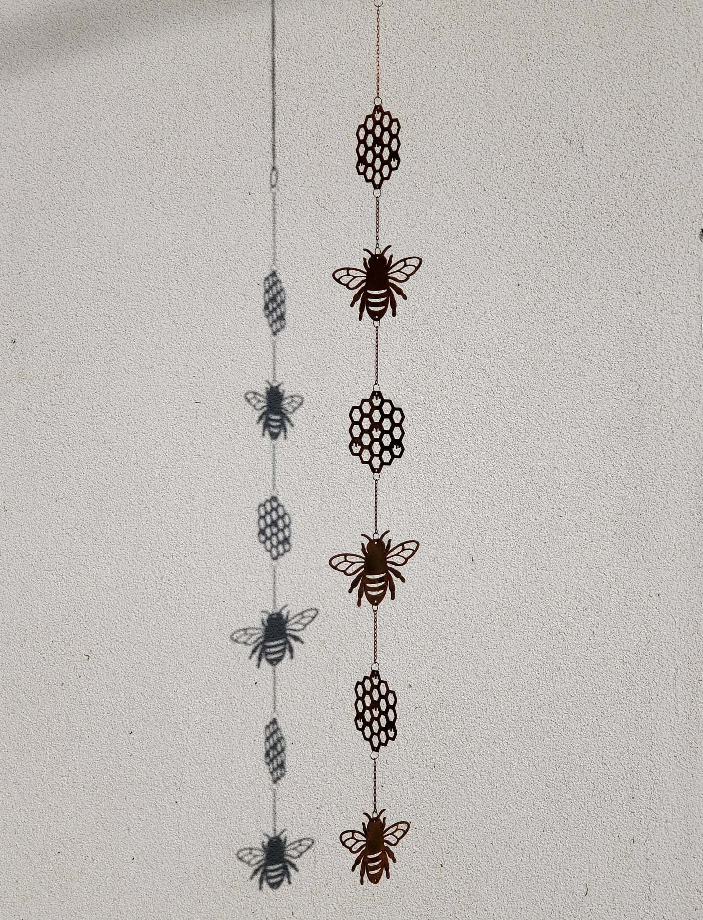 Side angle view of the full bee and honeycomb wind spinner, showing how the metal pieces connect and hang vertically