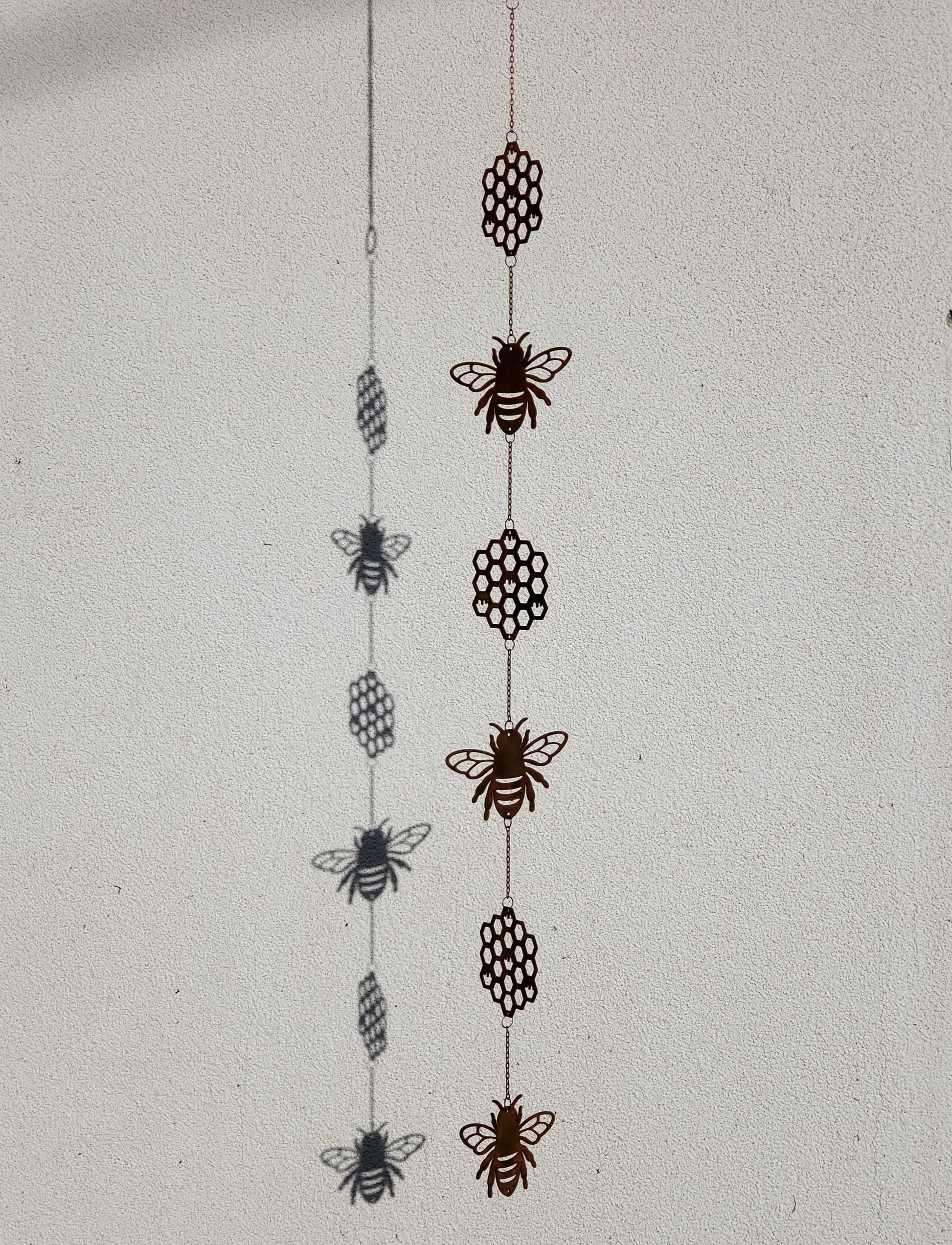 Side angle view of the full bee and honeycomb wind spinner, showing how the metal pieces connect and hang vertically